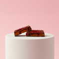 Load image into Gallery viewer, Goodio Blueberry Pie chocolate praline on a white pedestal against a pink background