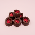 Load image into Gallery viewer, Goodio Salted Caramel Raspberry Bomb chocolate pralines on a light pink background