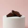 Load image into Gallery viewer, Goodio Lemon & Sea Salt chocolate praline on a pink background