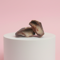 Load image into Gallery viewer, Goodio chocolate praline on a white cylindrical stand with a pink background