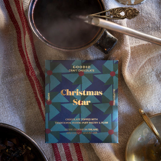 Goodio Craft Chocolate Christmas Star with a mug of hot chocolate on a textured surface.
