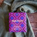 Load image into Gallery viewer, Purple and gold box of Rum Raisin chocolate on a textured green fabric background
