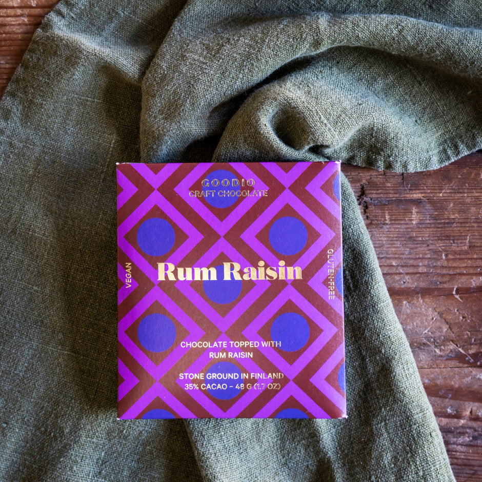 Purple and gold box of Rum Raisin chocolate on a textured green fabric background